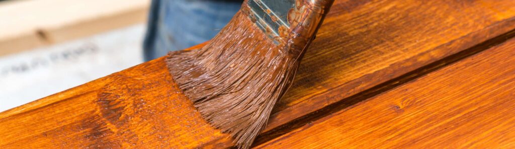 Painter with paintbrush painting wooden surface